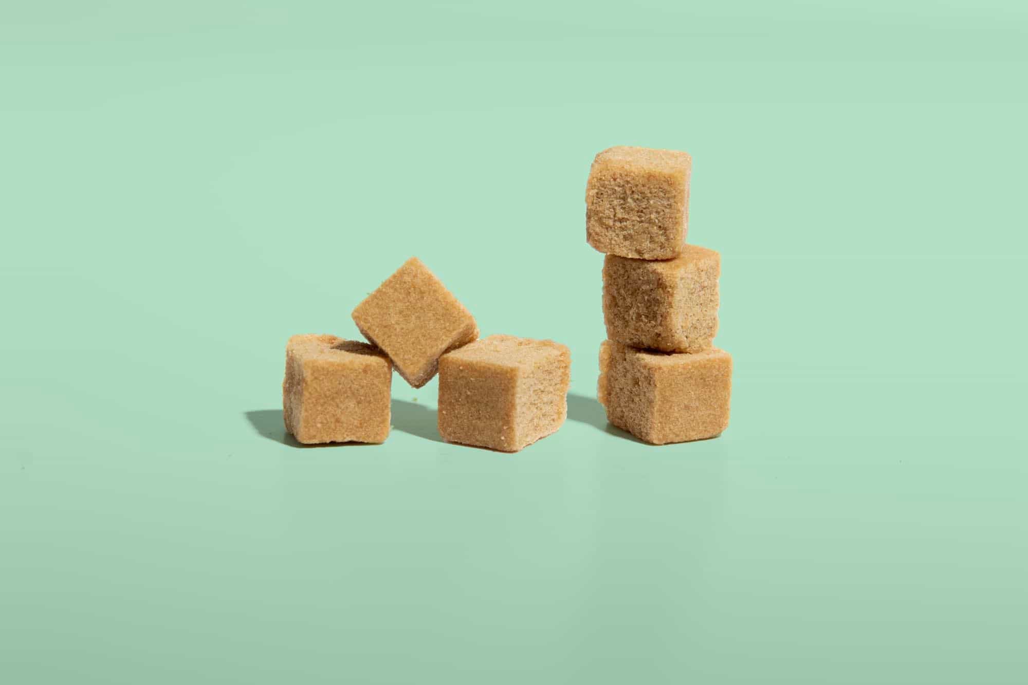 Brown sugar cubes arranged on a light green background.